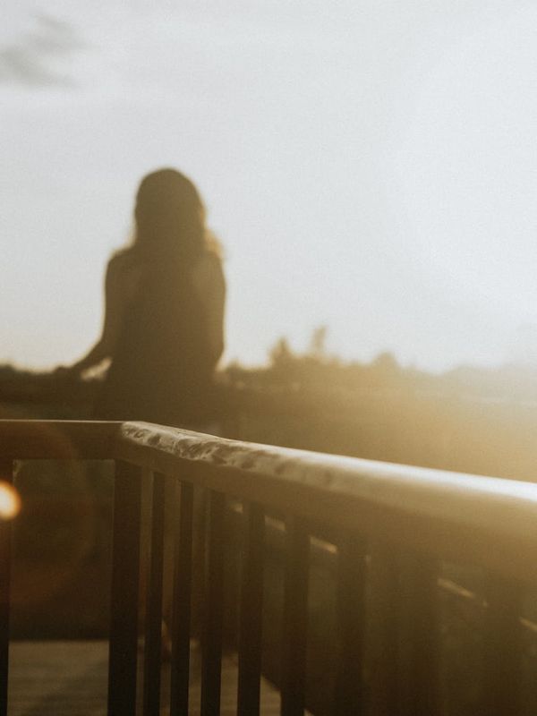Silhouette of a person stretching during sunrise with warm light.